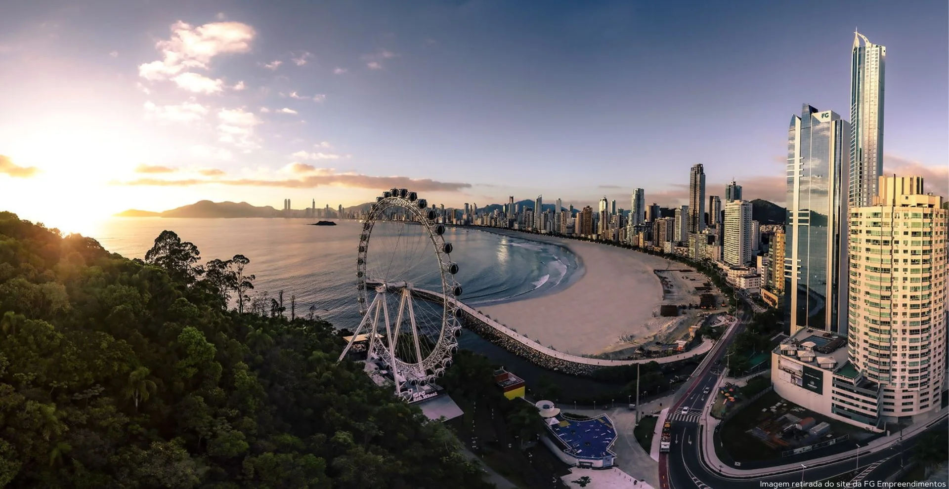 Vista aérea de Balneário Camboriú ao pôr do sol, com a roda-gigante e a orla